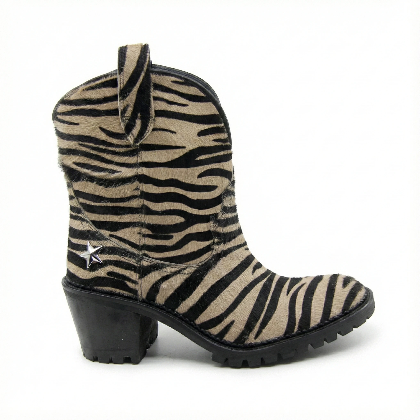Zebra print pony hair Western ankle boot with a chunky black heel, lug sole, pull tab, and silver star stud on shaft.