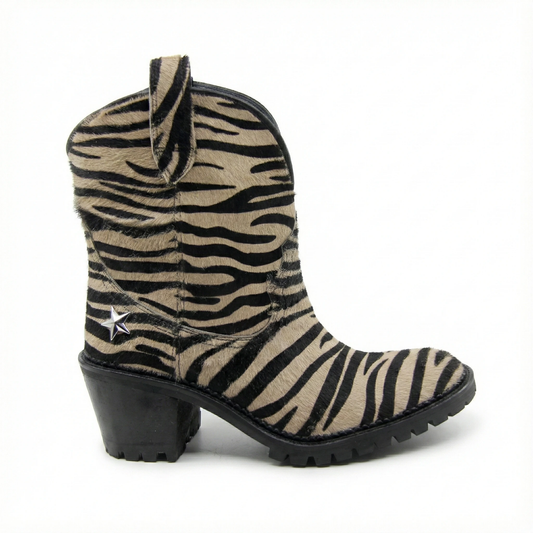 Zebra print pony hair Western ankle boot with a chunky black heel, lug sole, pull tab, and silver star stud on shaft.