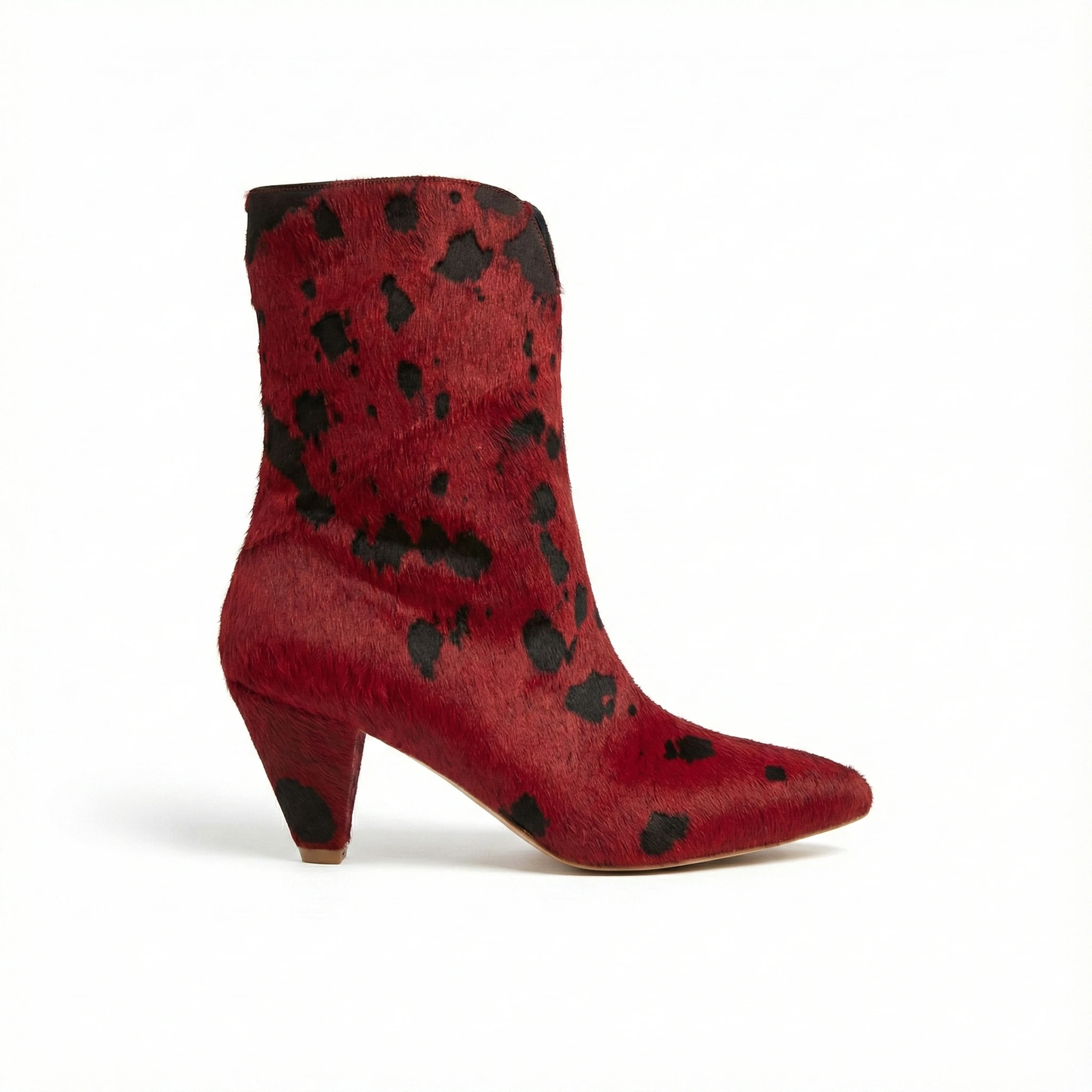 Red pony-hair ankle boot with irregular black spots, pointed toe and chunky mid-height heel, side view.
