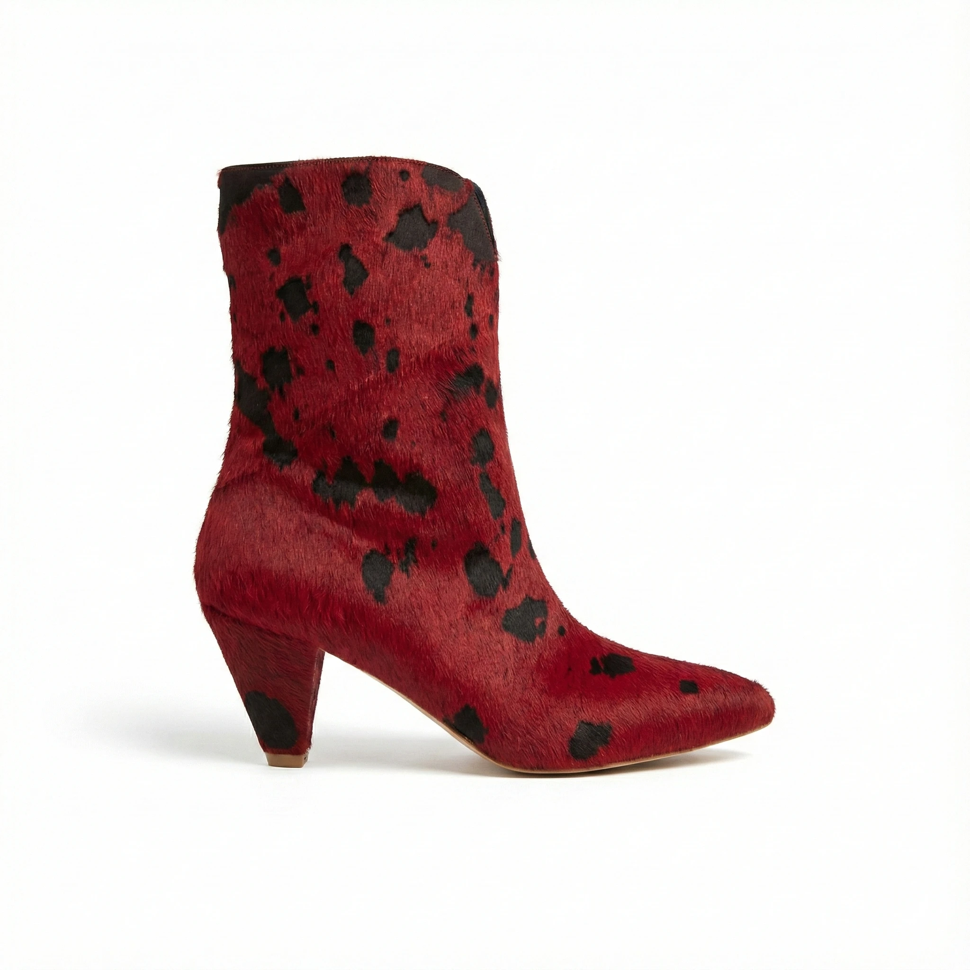 Red pony-hair ankle boot with irregular black spots, pointed toe and chunky mid-height heel, side view.