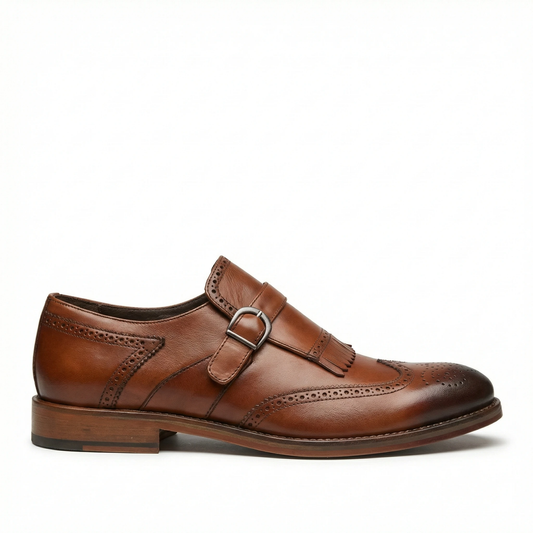 Brown leather wingtip monk strap shoe with a single buckle and fringe kiltie; brogue perforations on toe and along the sides, stacked heel.